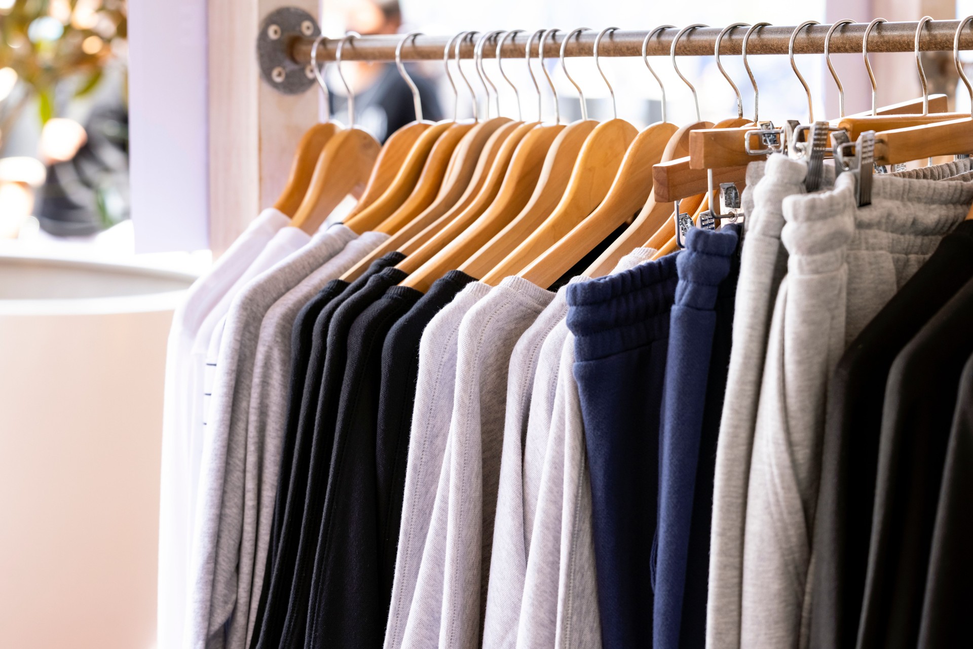 Row of knitted hoodies and pants, sports sweaters hanging on a hangers in Retail store, close-up