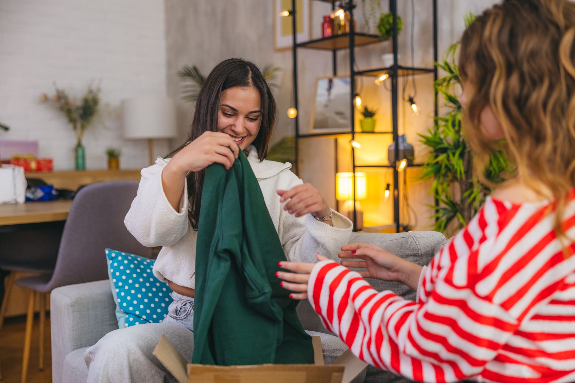 Two female friends unboxing a package of clothing at home